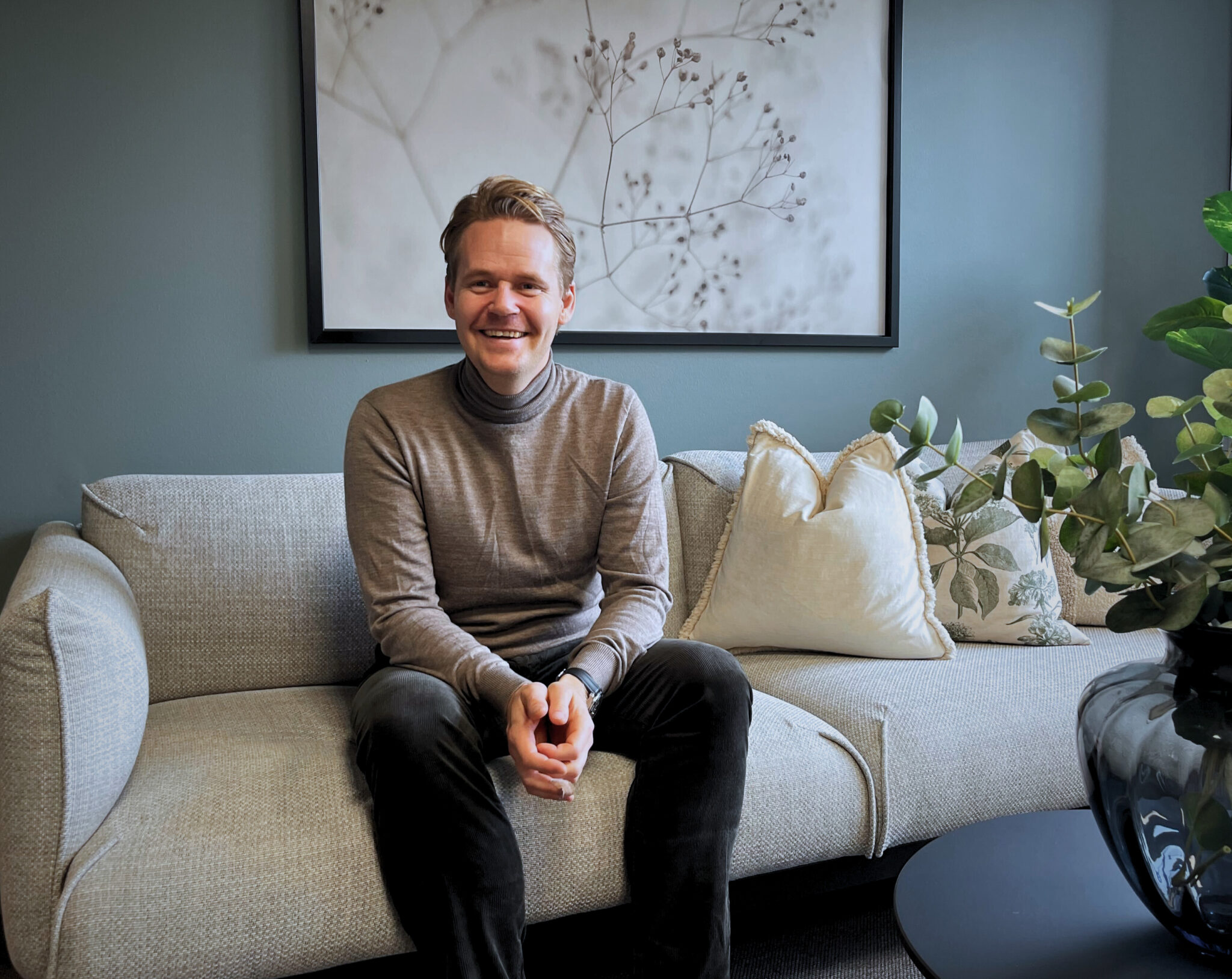 Bilde av Henrik Notevarp, salgsdirektør i Pexip Norge. Sitter på en grå sofa og smiler til kamera.